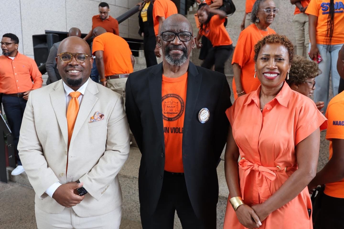 From left to right, Cory Penn, Robert Clopton Sr., and Samantha Ingram stand together during a Project Wear Orange event in Mobile, Alabama, supporting gun violence awareness, prevention, and community engagement initiatives.