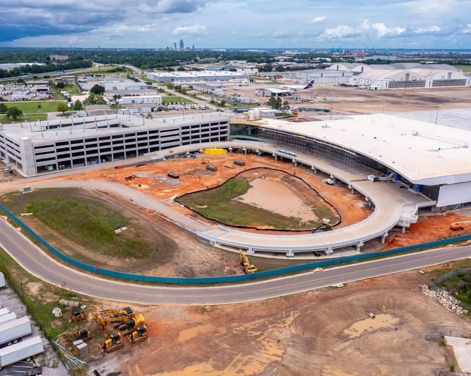 An aerial view of the active construction site at the Mobile International Airport BFM terminal showing the parking deck and main terminal progress.