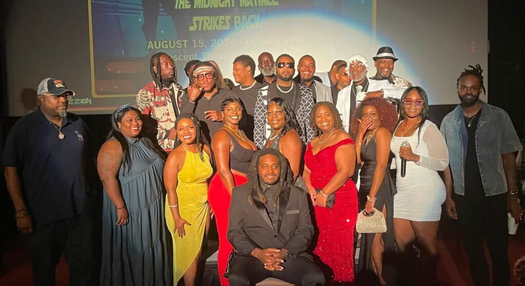 Director Bama Boy Buck seated in the center with the large ensemble cast and crew of Gamin: Pray for My Life gathered on stage for a group photo at the theater.