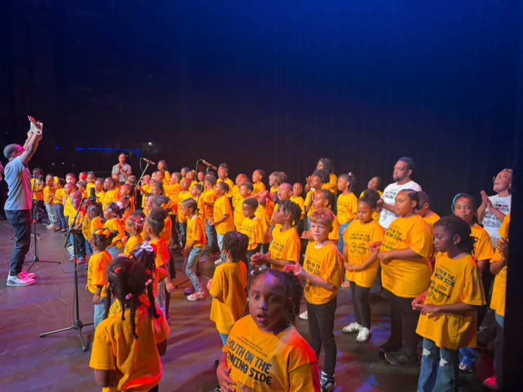 Children and youth participants in matching yellow Youth On The Winning Side t-shirts gathered on stage during the 35th session.