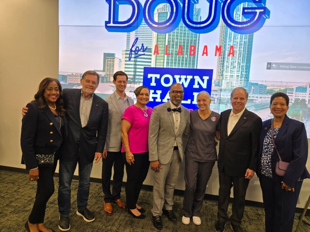Doug Jones and Phil Ensler pose with State Representatives including Senator Vivian Figures, Adline Clark, and Napoleon Bracy alongside community leaders after the Mobile town hall.