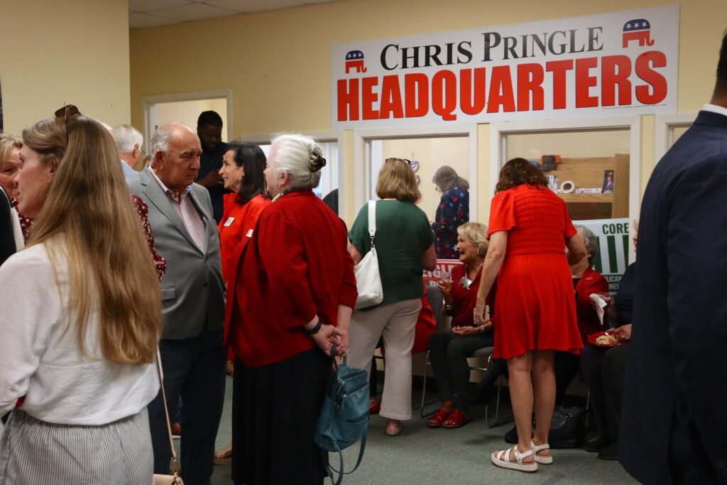 A group of community members mingling inside the headquarters beneath a banner reading "Chris Pringle Headquarters."