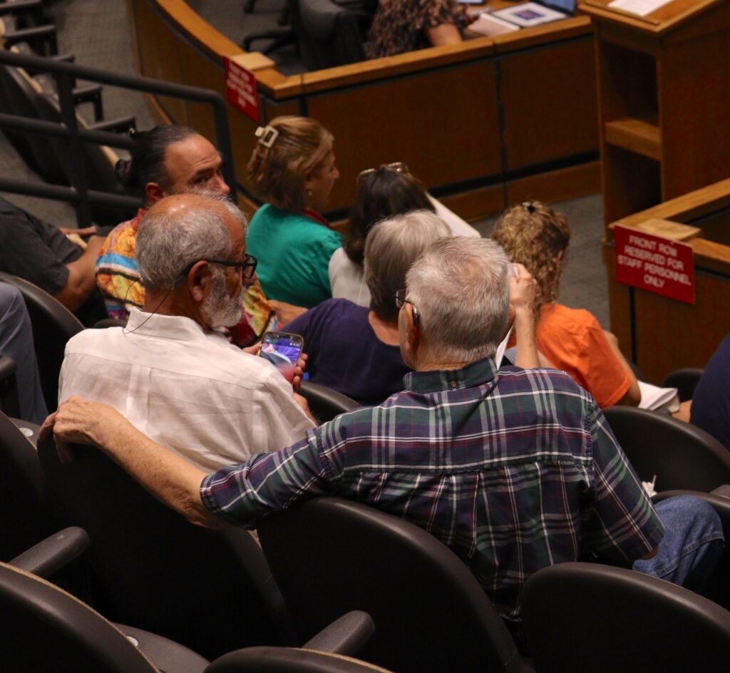 Members of the public seated in the audience during the public hearing at Government Plaza.