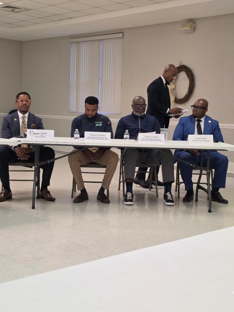 Brandon Colvin, Phelon Carter, Shad Collins, and Councilman Cory Penn sit behind a long table with their respective name cards.