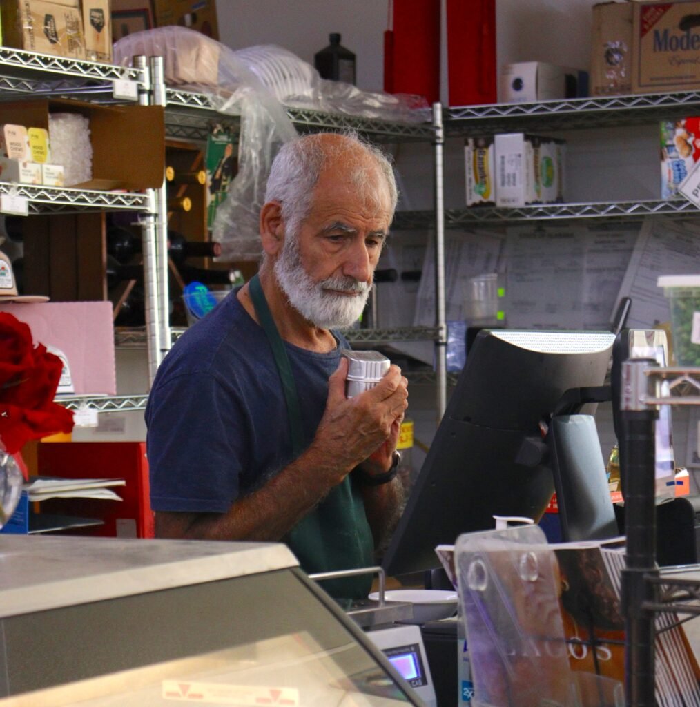 Food Pak International owner Reza Hejazi standing behind the grocery checkout counter.