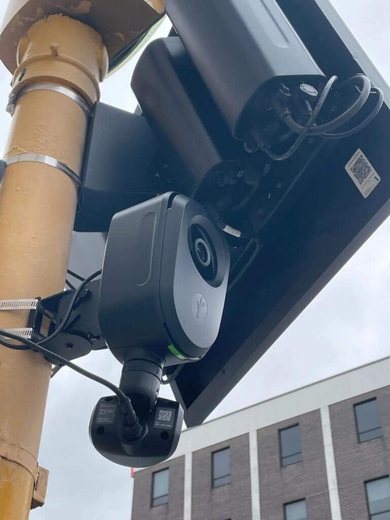 Close-up view of an optical character recognition camera mounted on a pole against a building.