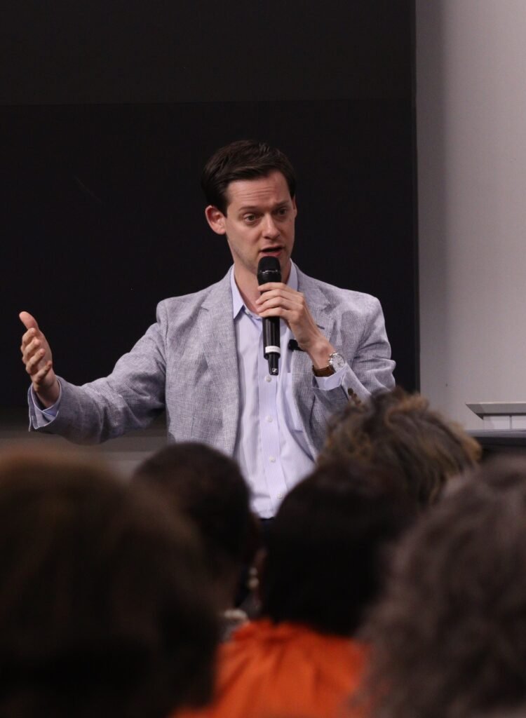 Phil Ensler gesturing while speaking to the audience at the town hall.