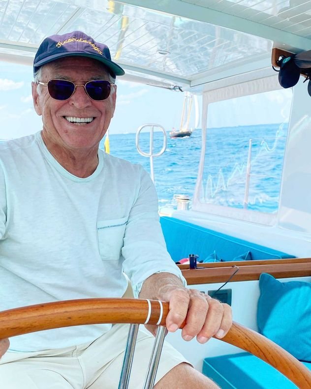 Jimmy Buffett at the helm of a boat on the water.
