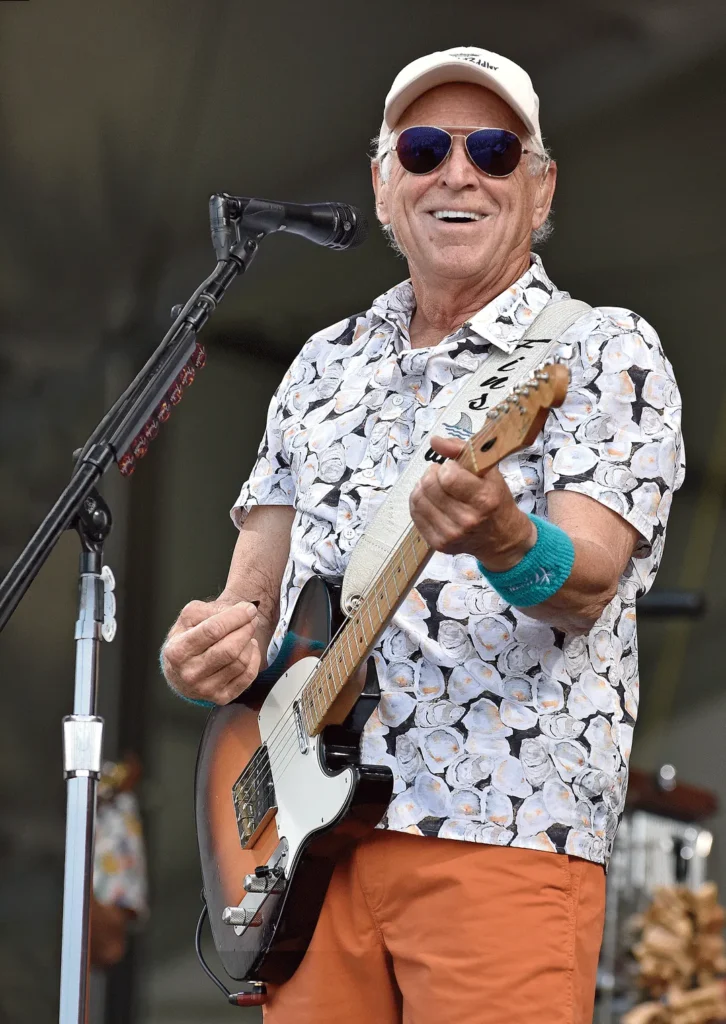 Jimmy Buffett performing live on stage with a guitar.