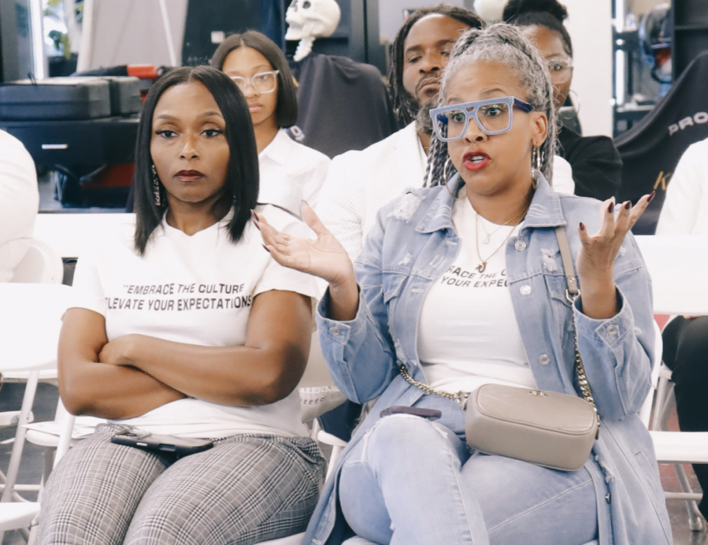 Great Day Latte owner Kimberly Knight speaking and gesturing during the audience discussion at the Barbershop Talk Who Speaks for Us Mobile AL event.